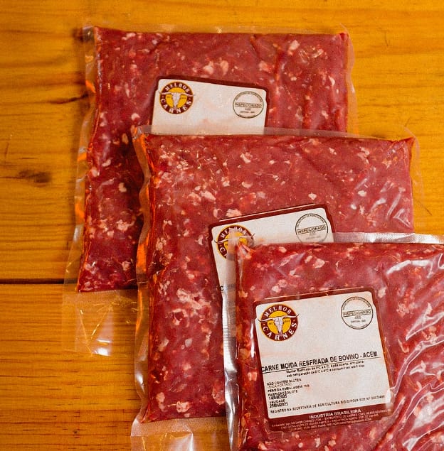 Pacotes de carne moída resfriada embalados e etiquetados sobre bancada de madeira